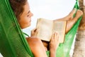 Happy and beautiful woman lying in the hammock and reading book Royalty Free Stock Photo