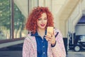 Happy beautiful woman reading good news message or seeing photos on her mobile phone. Smiling red head curly hair girl, isolated Royalty Free Stock Photo