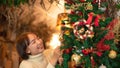 Happy beautiful woman in sweater holding santa boots and decoration to decorate on christmas tree for celebration Royalty Free Stock Photo