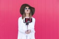 Happy beautiful woman taking a selfie with smartphone over red b Royalty Free Stock Photo