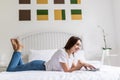 Happy casual beautiful woman working on a laptop sitting on the bed in the house. Royalty Free Stock Photo