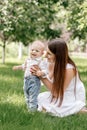 Happy beautiful woman, young mother playing with her adorable baby son, cute little boy, enjoying together a sunny warm Royalty Free Stock Photo