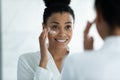 Happy beautiful young african woman applying creme.