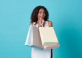 Happy beautiful young african woman in white dress and hand holding shopping bag isolated over blue background Royalty Free Stock Photo