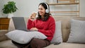 Happy Asian female wearing headphones, watching movie on her laptop in her living room Royalty Free Stock Photo