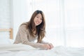 Happy beautiful young Asian woman waking up in morning, sitting on bed, stretching in cozy bedroom. Royalty Free Stock Photo