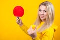 Happy beautiful young blonde woman in casual yellow sporty clothes play ping pong, holding a ball and racquet Royalty Free Stock Photo