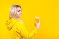 Happy beautiful young blonde woman in yellow casual sporty clothes holding orange juice glass Royalty Free Stock Photo