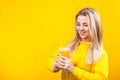 Happy beautiful young blonde woman in yellow casual sporty clothes holding orange juice glass Royalty Free Stock Photo