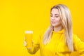 Happy beautiful young blonde woman in yellow casual sporty clothes holding orange juice glass Royalty Free Stock Photo