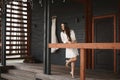 Happy and beautiful young brunette bride with wedding hairstyle and makeup, wearing nightwear, standing on a porch and Royalty Free Stock Photo