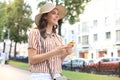 Happy beautiful young brunette girl using mobile phone while walking outdoors Royalty Free Stock Photo