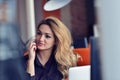 Happy beautiful young business woman sitting and talking on cell phone in office Royalty Free Stock Photo