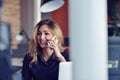 Happy beautiful young business woman sitting and talking on cell phone in office Royalty Free Stock Photo