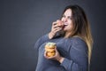 Happy beautiful young caucasian plus size model posing with donuts on a gray studio background Royalty Free Stock Photo
