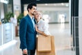 Happy beautiful young couple holding shopping paper bags with purchases and hugging looking upon showcase at mall. Royalty Free Stock Photo