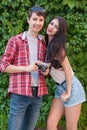 Happy beautiful young couple near green wall with camera. looking at camera. Royalty Free Stock Photo