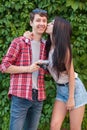 Happy beautiful young couple near green wall with camera. looking at camera. Royalty Free Stock Photo