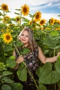 A happy, beautiful young girl is standing in a large field of sunflowers. Royalty Free Stock Photo