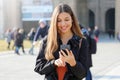 Happy beautiful young high school girl with smart phone outdoors on sunny spring day texting and smiling Royalty Free Stock Photo