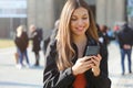 Happy beautiful young high school girl with smart phone outdoors on sunny spring day texting and smiling Royalty Free Stock Photo