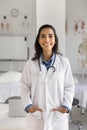 Happy beautiful young Hispanic doctor woman standing in medical office Royalty Free Stock Photo