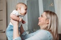 Happy beautiful young mother holds a little baby girl in her arms and looks at her with love Royalty Free Stock Photo