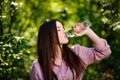 Happy beautiful young thirsty woman drinking water from transpar