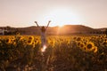 Happy Young Woman With Arms Opened From Her Back In A Sunflower Field At Sunset