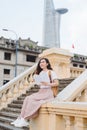 Happy beautiful young woman with backpack and book sitting on stairs outdoors Royalty Free Stock Photo