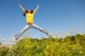 Happy and beautiful young woman in a bright yellow sweater and blue jeans jumping high in a sunny summer field Royalty Free Stock Photo