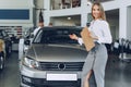 Happy beautiful young woman car dealer in showroom Royalty Free Stock Photo