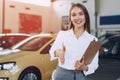 Happy beautiful young woman car dealer in showroom Royalty Free Stock Photo