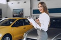 Happy beautiful young woman car dealer in showroom Royalty Free Stock Photo