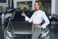 Happy beautiful young woman car dealer in showroom Royalty Free Stock Photo