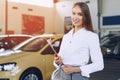 Happy beautiful young woman car dealer in showroom Royalty Free Stock Photo