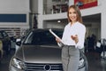 Happy beautiful young woman car dealer in showroom Royalty Free Stock Photo