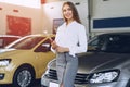 Happy beautiful young woman car dealer in showroom Royalty Free Stock Photo