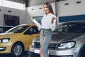 Happy beautiful young woman car dealer in showroom Royalty Free Stock Photo