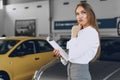 Happy beautiful young woman car dealer in showroom Royalty Free Stock Photo