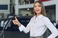 Happy beautiful young woman car dealer in showroom Royalty Free Stock Photo