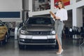 Happy beautiful young woman car dealer in showroom Royalty Free Stock Photo