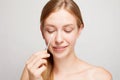 Happy beautiful young woman cleaning skin by cotton swab.