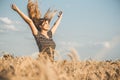 Happy beautiful young woman enjoying nature, raising hands on background of cloudy sky in wheat field, girl breathe breathes Royalty Free Stock Photo