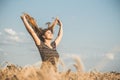 Happy beautiful young woman enjoying nature, raising hands on background of cloudy sky in wheat field, girl breathe breathes Royalty Free Stock Photo