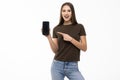 Happy beautiful young woman holding blank screen mobile phone and pointing finger over white background Royalty Free Stock Photo