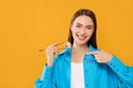 Happy beautiful young woman holding sushi roll with chopsticks on orange background. Space for text Royalty Free Stock Photo