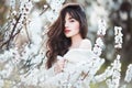 Happy beautiful young woman with long black healthy hair enjoy fresh flowers and sun light in blossom park. Royalty Free Stock Photo