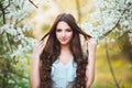 Happy beautiful young woman with long black healthy hair enjoy fresh flowers and sun light in blossom park at sunset. Royalty Free Stock Photo