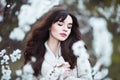 Happy beautiful young woman with long black healthy hair enjoy fresh flowers and sun light in blossom park at sunset. Royalty Free Stock Photo